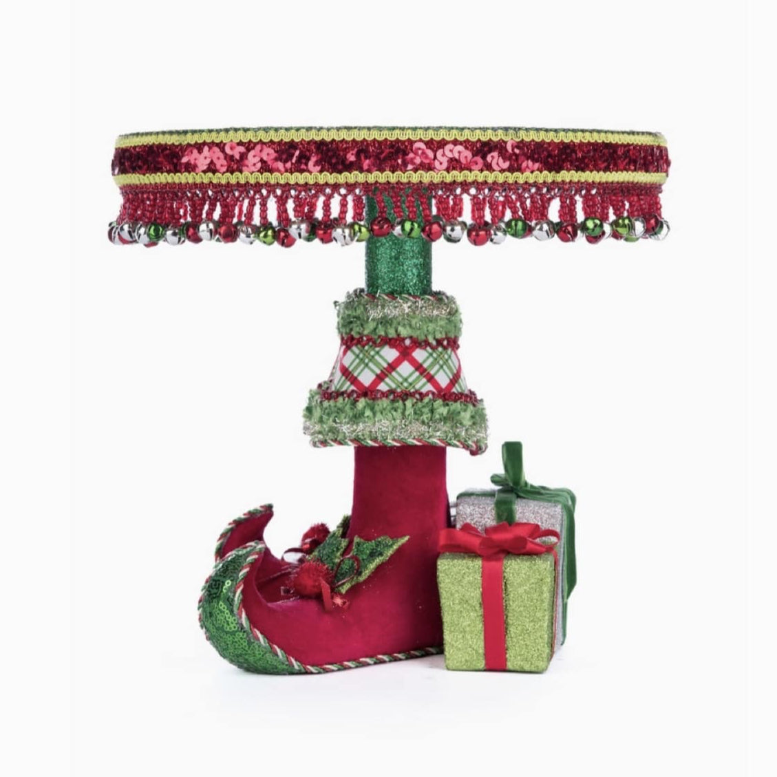 left side view of Food-safe resin Elf Boots Cake Plate (SKU 28-428347, GTIN 810074128339) decorated with sequins, beaded fringe, holly leaves, and jingle bells.