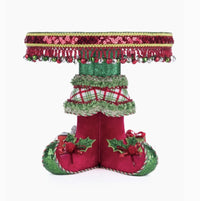 Katherine’s Collection Elf Boots Cake Plate (SKU 28-428347, GTIN 810074128339) with velvet elf shoes, sequins, jingle bells, and holly leaf tray.