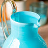 Aqua handblown pitcher filled with water on a table with glasses