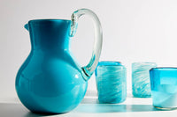 Glasses displayed with handblown pitcher on dining table