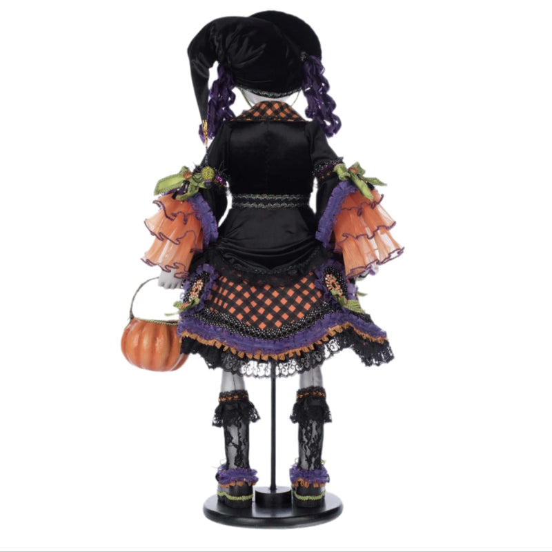 Decorative witch figurine with a pumpkin and broomstick on a white background