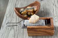 Fresh parmesan being grated into the olive wood box