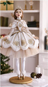Decorative doll in a white and gold dress with a tiara, standing on a wooden base.