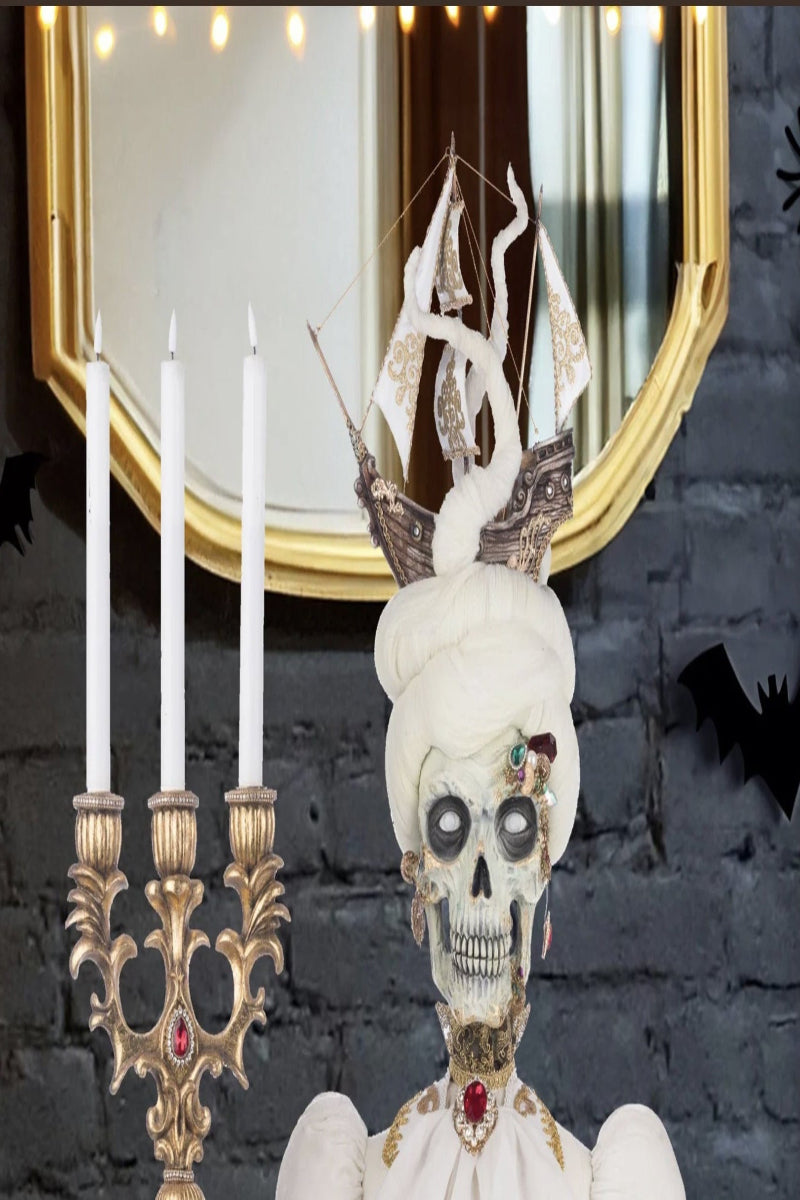 Decorative skeleton figure with candles and a mirror in a Halloween-themed setting.