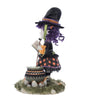 Left Side view of Katherine's Collection Poppy Broomson Witch standing over her cauldron reading a spell book, with pumpkins at her feet in an orange and black buffalo plaid dress and jeweled accents. and black witches hat