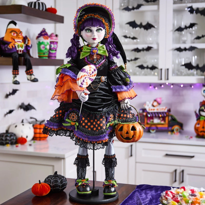 Halloween-themed doll with colorful outfit and pumpkin, set against a festive background.