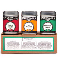 Three tins of Spicewalla taco seasoning blends displayed together on a rustic kitchen counter