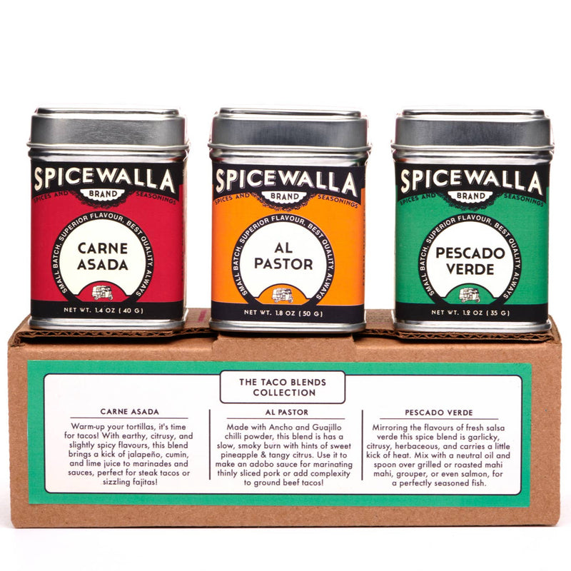 Three tins of Spicewalla taco seasoning blends displayed together on a rustic kitchen counter