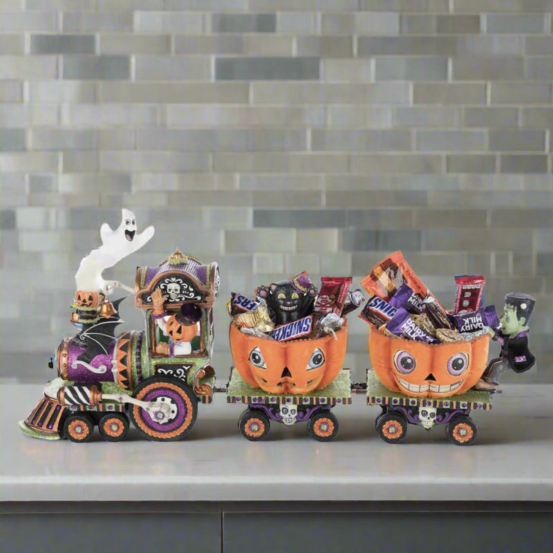 Scene with the train set displayed on a Halloween-decorated mantel or shelf.