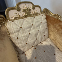 Close-up of a decorative upholstery with gold frame and beige cushion.