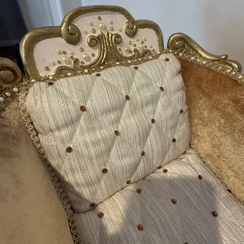 Close-up of a decorative upholstery with gold frame and beige cushion.