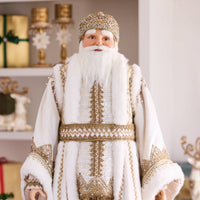 Man in a traditional Russian Christmas costume standing in a decorated room with a Christmas tree and gifts.