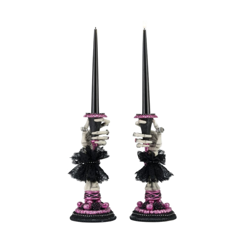 Two skeleton hand candle sticks with decorative elements on a white background.