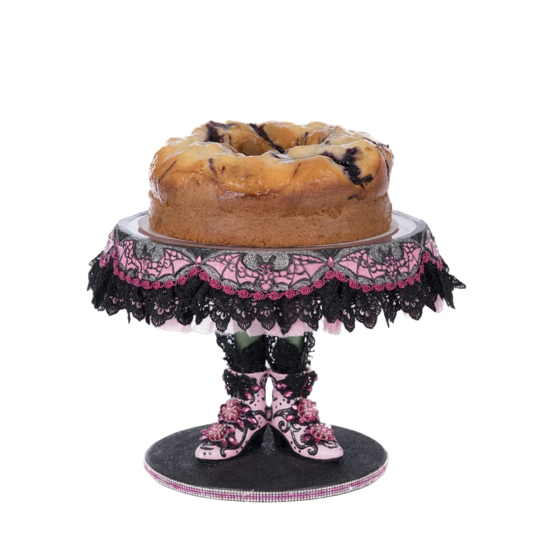 Katherine’s Collection Witch Boots Cake Plate displayed with Halloween cake, elegant hand-painted collectible dessert stand.