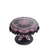 top view of Katherine’s Collection Witch Boots Cake Plate with glitter and lace bat wing design under clear food safe surface.