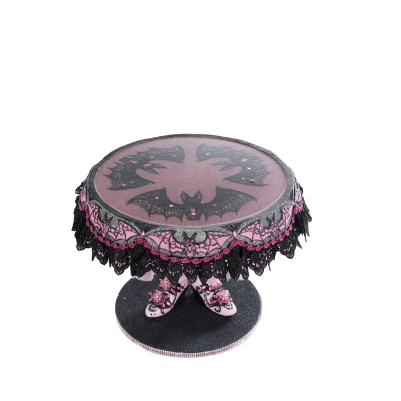 top view of Katherine’s Collection Witch Boots Cake Plate with glitter and lace bat wing design under clear food safe surface.
