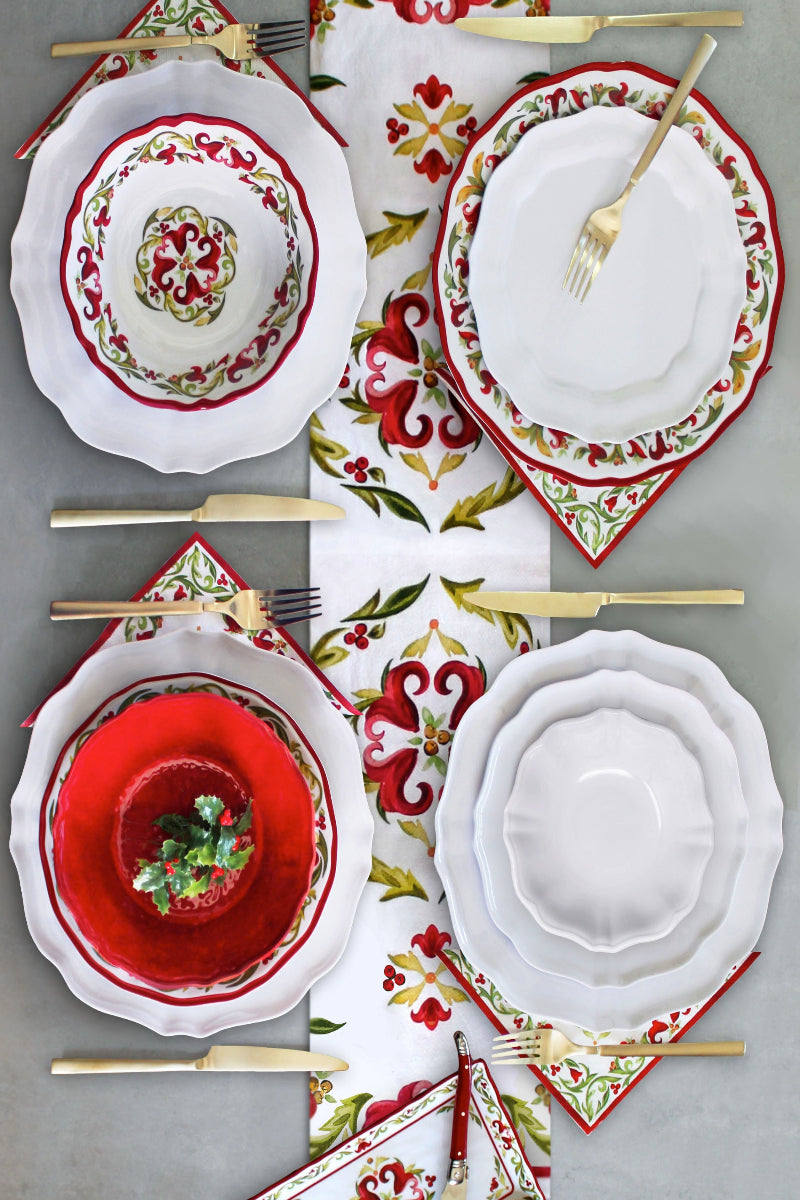 Set of Christmas-themed dinnerware with red, green, and white patterns on a gray surface.