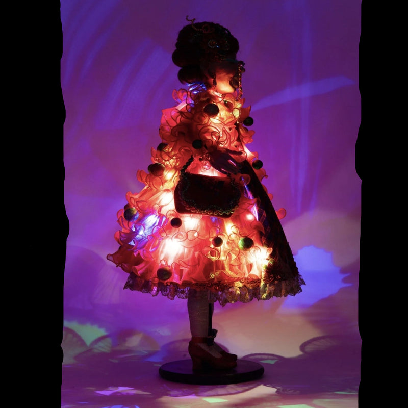 right side view of Holiday Magic Mae doll featuring hidden twinkle lights in her red tulle coat.